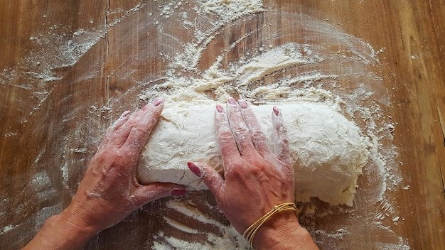 Mains pétrissant une pâte à pain sur plan de travail fariné